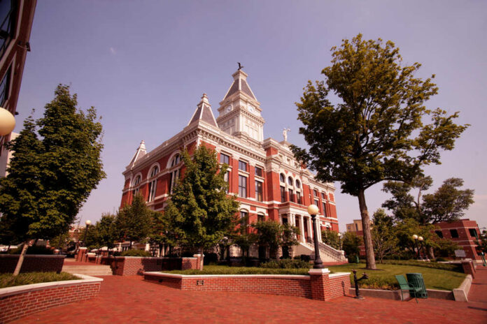 Historic red-brick courthouse with clock tower and trees in a sunny plaza