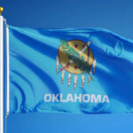 Oklahoma state flag waving against a blue sky