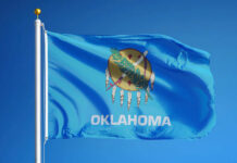 Oklahoma state flag waving against a blue sky