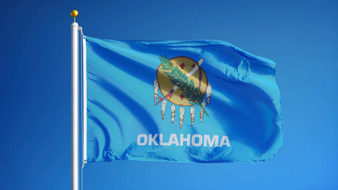 Oklahoma state flag waving against a blue sky