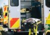 Ambulance with open rear doors and an empty stretcher outside