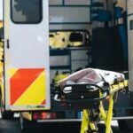 Ambulance with open rear doors and an empty stretcher outside