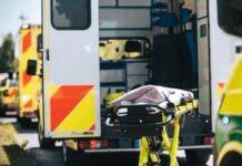 Woman Dies After Bridge Jump Accident Ambulance with open rear doors and an empty stretcher outside