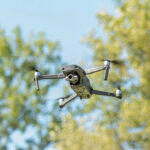 Russia Plot Alleged, Receipts Missing A drone flying against a backdrop of green trees and a blue sky