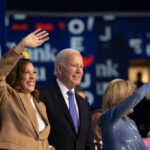 Group of political figures waving at an event, smiling and engaging with the audience