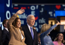 Group of political figures waving at an event, smiling and engaging with the audience