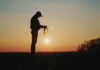 Vineyards Warn Of Economic Oblivion Silhouette of a farmer holding soil against a sunset backdrop