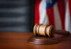 White House Valor Beats Wall Street Verdict A wooden gavel resting on a round base with a blurred American flag in the background