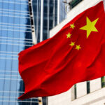 Chinese flag waving in front of modern buildings