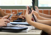 UK’s Big Brother Move Sparks Uproar Students in a classroom using smartphones for a group activity
