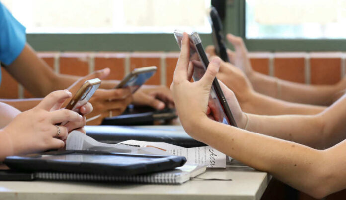 shutterstock_1847575498 Students in a classroom using smartphones for a group activity