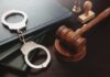 Federal Judge ARRESTED Over Parking Spat Handcuffs and a gavel on a desk with legal books