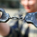 Pride Founder Arrest Rocks Community Close-up of handcuffs being held by a person
