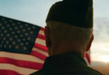Decades Later, Gulf War Veterans Still Await Justice A veteran in uniform standing in front of an American flag during sunset