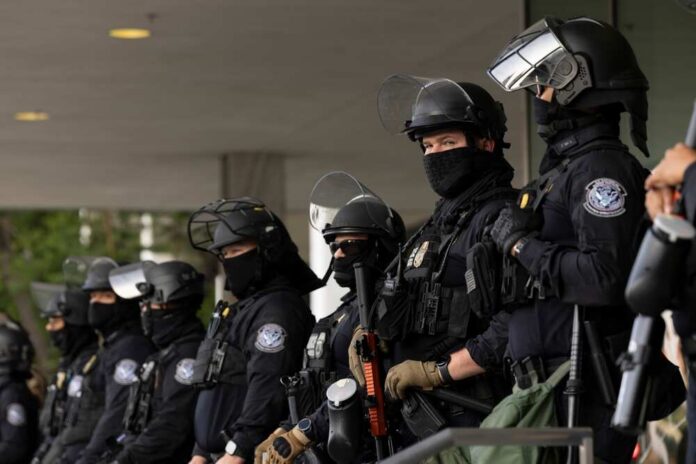 Police officers in riot gear stand in a line