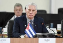 Cuban representative at a political meeting with a flag in front
