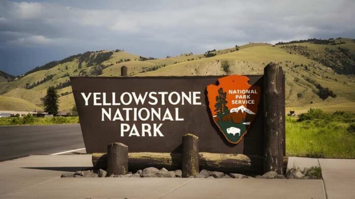 2483931935 Yellowstone National Park entrance sign beside a road with rolling hills