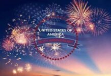Fireworks burst over a twilight sky with a USA anniversary emblem
