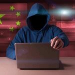 China Scoops 220M Voter Files Hooded figure using a laptop with red cybersecurity graphics