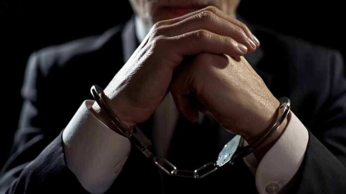 Businessperson in handcuffs with hands clasped