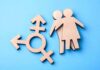 Senate Candidate Faces Transgender Care Backlash Wooden transgender symbol and two human figures on blue background