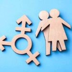 Senate Candidate Faces Transgender Care Backlash Wooden transgender symbol and two human figures on blue background
