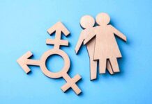Senate Candidate Faces Transgender Care Backlash Wooden transgender symbol and two human figures on blue background