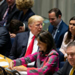 A group of political leaders seated at a United Nations meeting, engaged in discussion