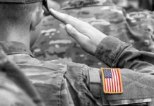 Iran’s Reach Exposed Inside US Hub Soldier saluting with an American flag patch on sleeve