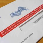 USPS Mail Ballot Rule Advances Mail-in ballot envelope with red label on wooden table