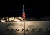 Pentagon Union Purge Sparks Court Showdown A small American flag positioned in front of the word 'PENTAGON' on a reflective surface