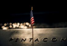 Pentagon Union Purge Sparks Court Showdown A small American flag positioned in front of the word 'PENTAGON' on a reflective surface