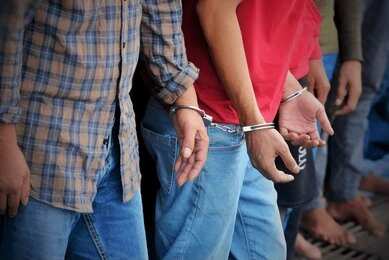 Handcuffed people standing in a line