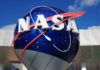 Private Craft Chases Aging NASA Telescope NASA logo displayed on a large blue globe against a clear sky