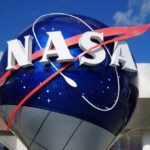 Private Craft Chases Aging NASA Telescope NASA logo displayed on a large blue globe against a clear sky