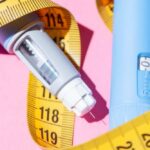 An insulin pen and measuring tape on a pink background