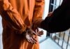 Prisoner in orange jumpsuit handcuffed by officer