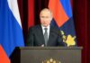 Trash Bin Bomb Kills Former Commander man in suit speaking at a podium with flags behind him