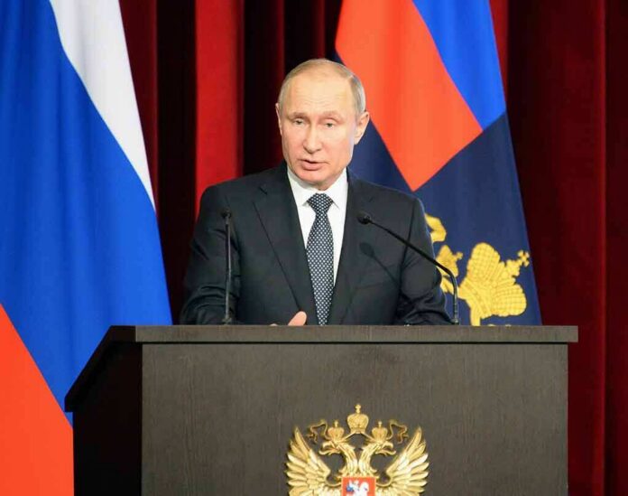 man in suit speaking at a podium with flags behind him