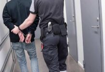 Abolish ICE Pledge Meets Brutal Reality Security officer escorts handcuffed person down hallway