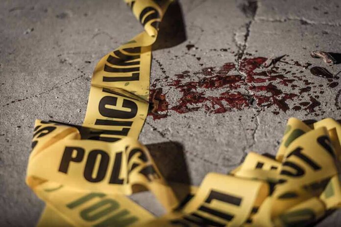 shutterstock_1089277004 Crime scene tape near blood on pavement