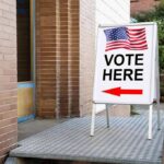 Sidewalk sign with American flag directing to a polling place