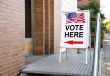 Trump’s Election Security Push Hits Court Sidewalk sign with American flag directing to a polling place