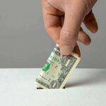 Donor Dollars Buy Tacos And Liquor? Hand inserting a folded dollar bill into a small slot