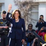 Pricey Malibu Buy Triggers Equity Backlash woman in navy suit waving at outdoor event