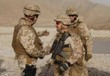 Soldiers in desert uniforms shake hands outdoors