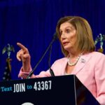 woman in pink suit speaking at a podium