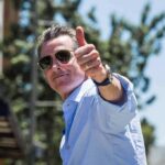 man in sunglasses giving a thumbs-up outdoors