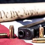 Handgun with bullets on American flag near parchment