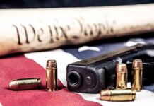 Quiet DOJ Move Rattles Gun Debate Handgun with bullets on American flag near parchment